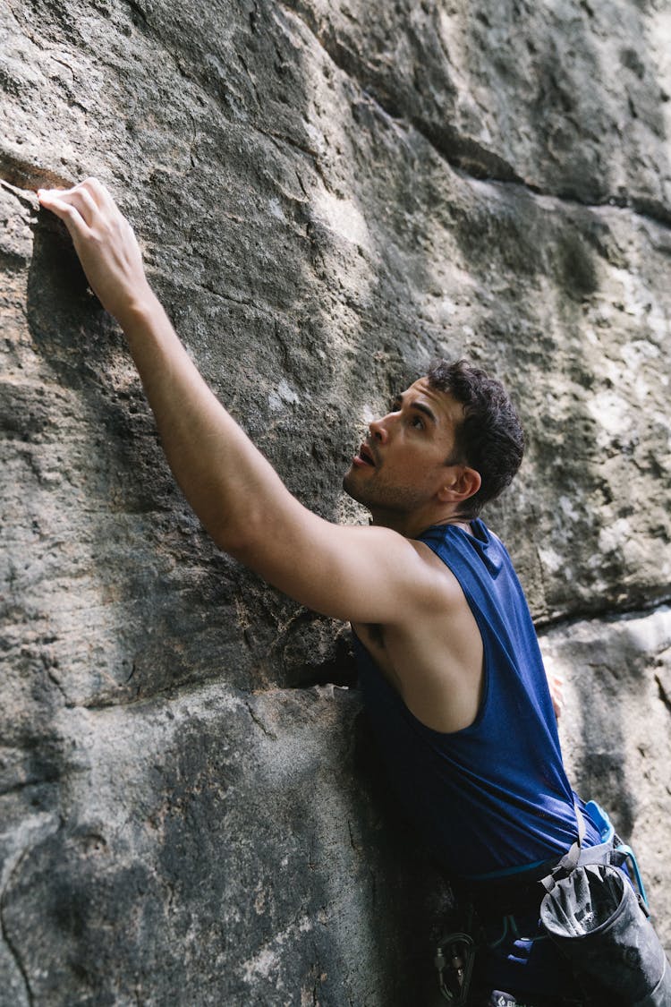 Man In Blue Tank Top Climbing Rocks 