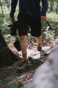 Close-up of a man hiking in a forest carrying camera gear, showcasing outdoor adventure.
