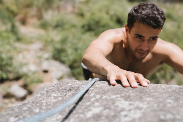 Young Shirtless Man Climbing Rock