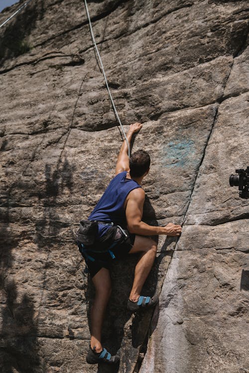 Free Man in Blue Shorts Climbing on Rock Stock Photo