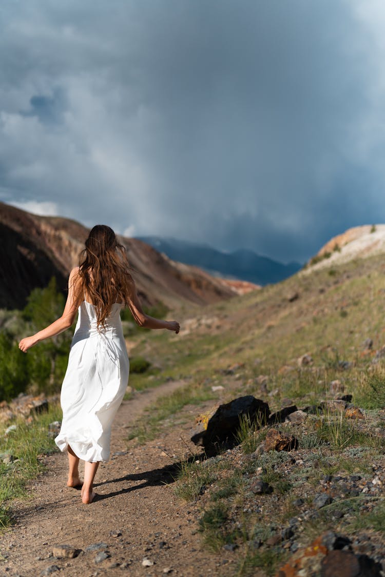 Back View Of A Woman In White Dress Walking On The Ground