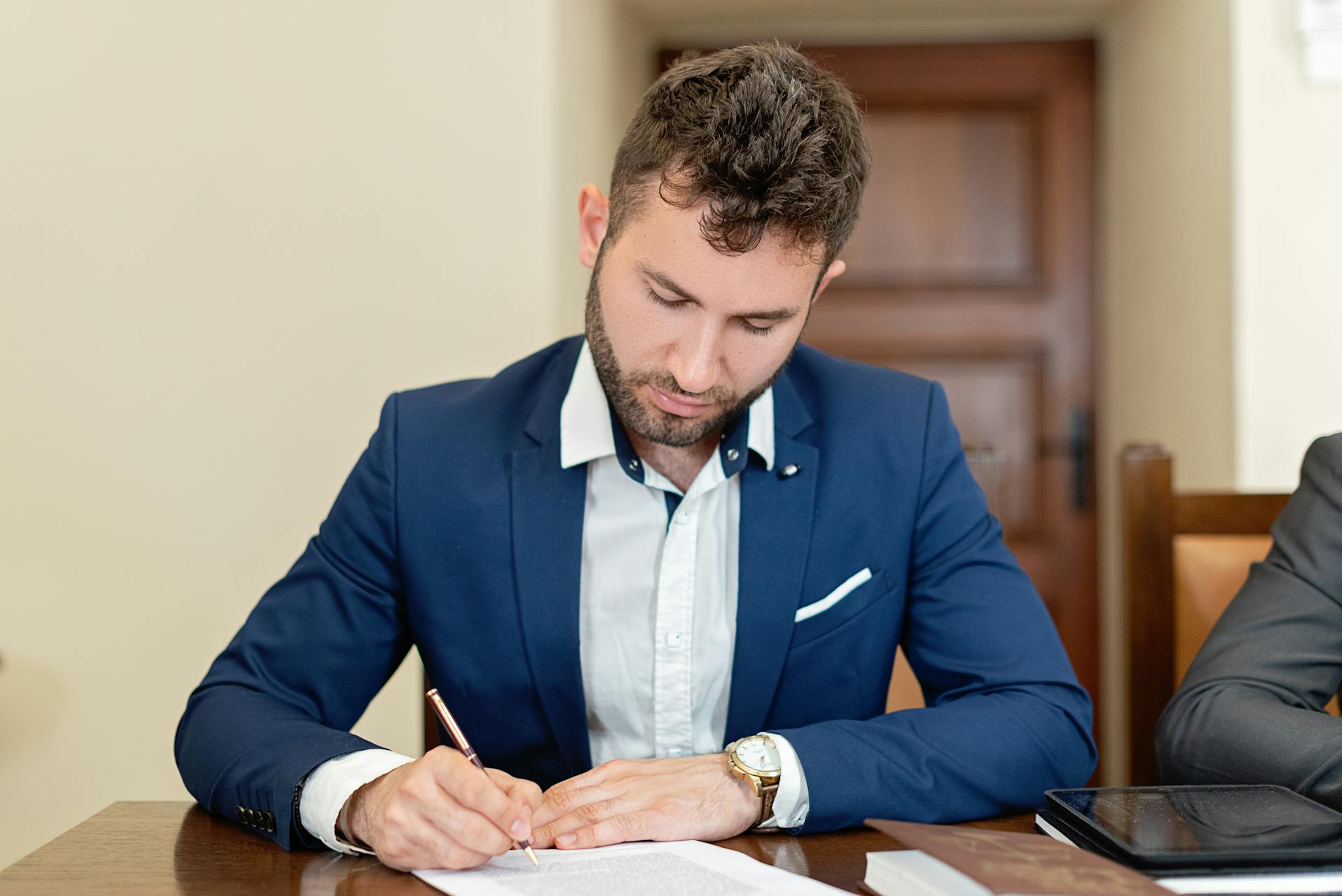 Man Sitting at a Table and Signing a Document