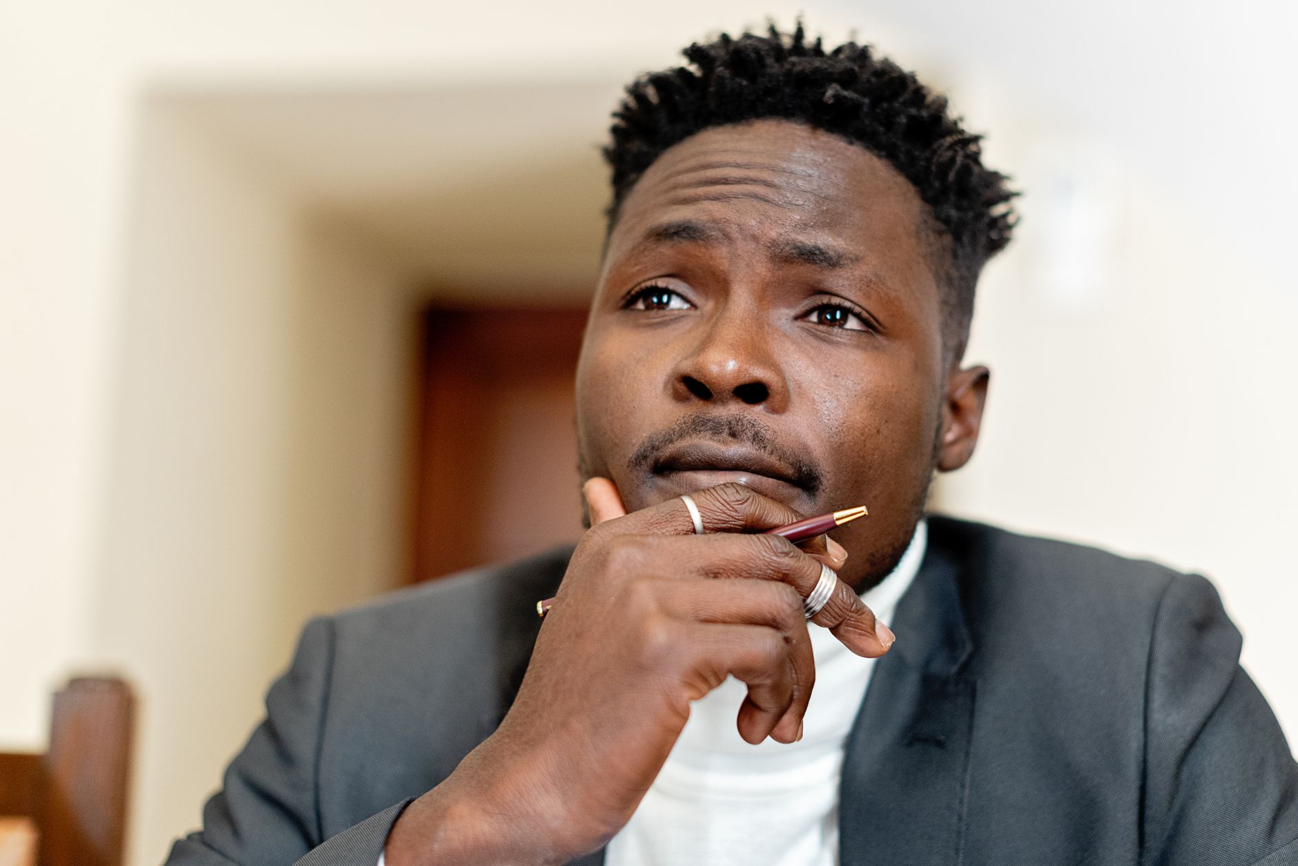 Close-up of a thoughtful businessman holding a pen, contemplating a decision indoors.