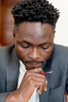 Close-up of a man in deep thought, holding a pen thoughtfully.