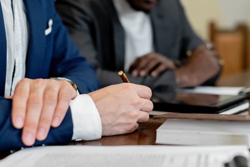 Free Close-up of hands writing at a business meeting. Professional attire and documents visible. Stock Photo