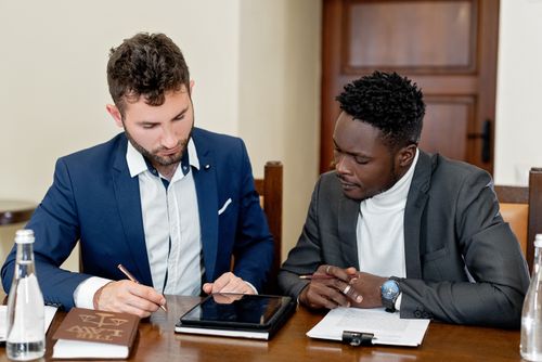 Free Two businessmen collaborating over documents and a digital tablet during a meeting. Stock Photo