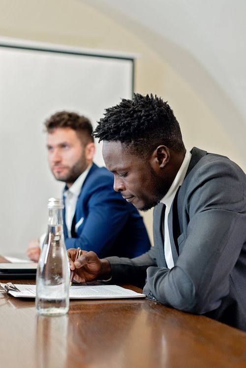 Free Focused businessmen reviewing documents in a modern office setting. Stock Photo
