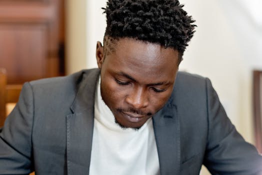 A concentrated adult man in a suit working indoors, showcasing focus and professionalism.