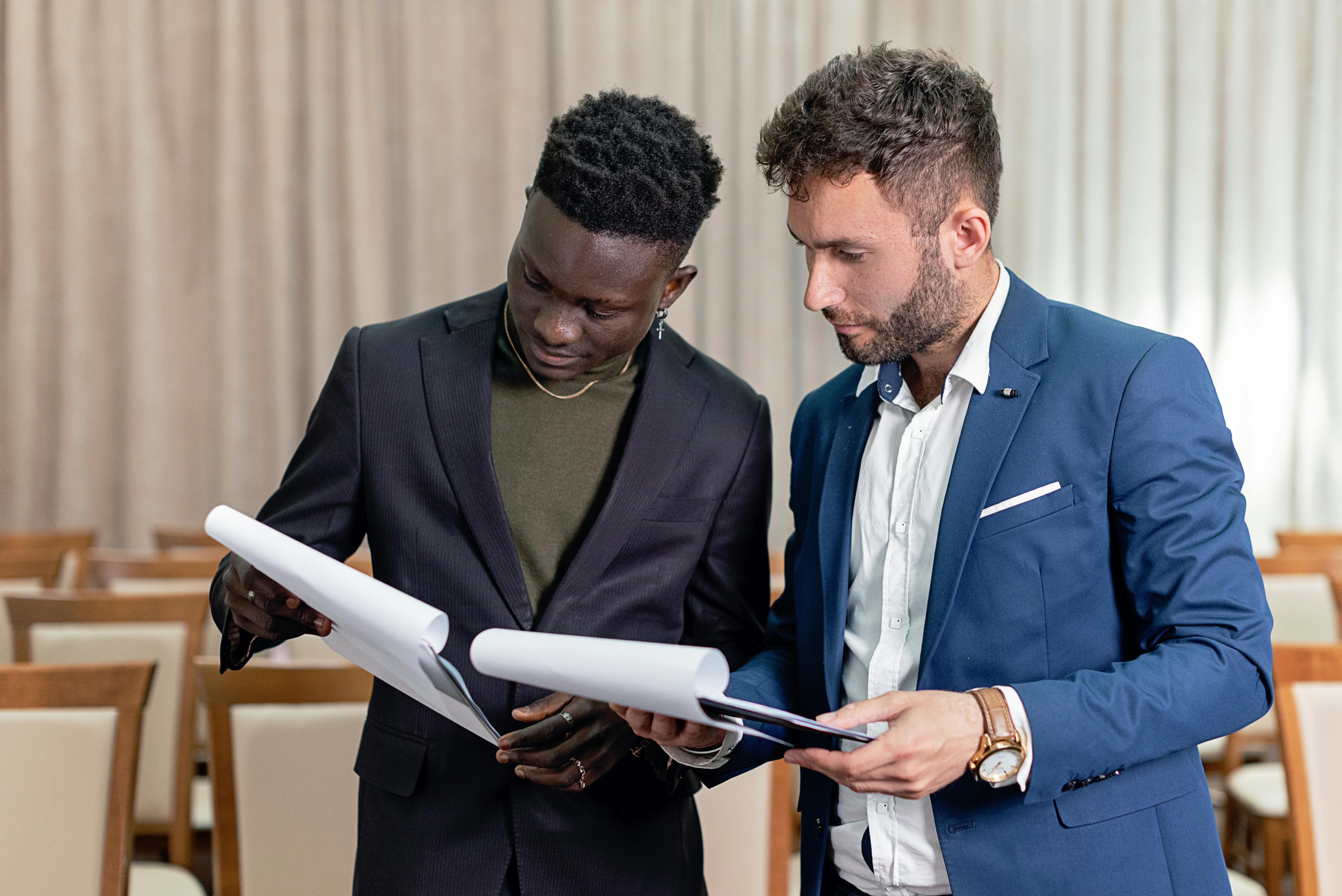 businessmen in black and blue suit having conversation while holding documents