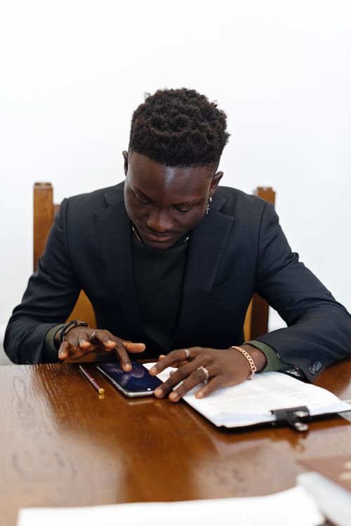 Free A professional man working in an office, using a smartphone with documents. Stock Photo