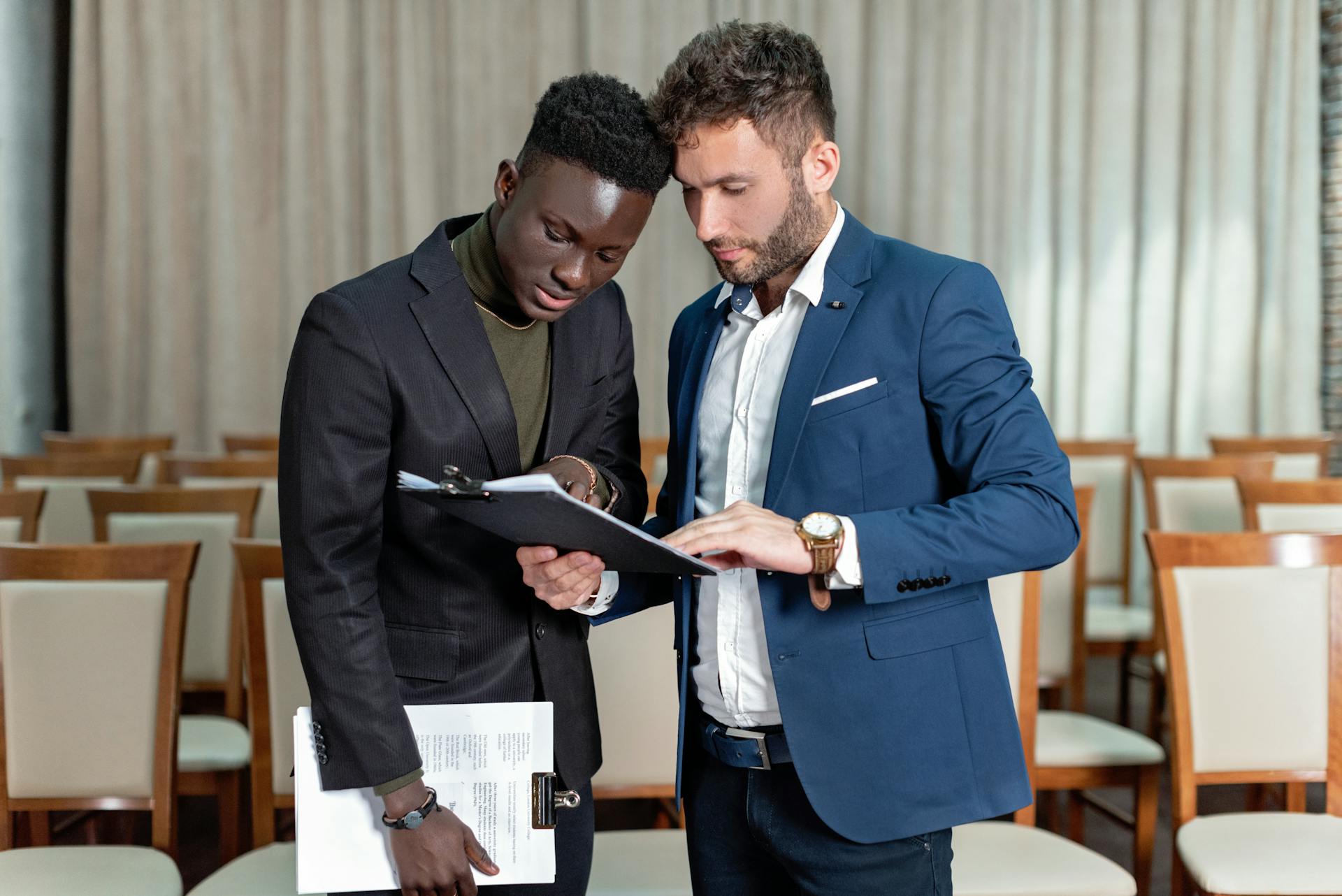 Two business professionals engaged in a detailed document review in a conference room.