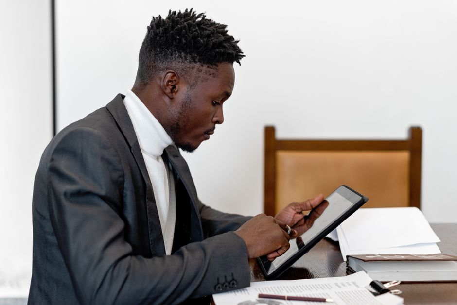 Empresario con traje elegante utilizando una tableta durante una reunión de oficina, concentrándose en la tecnología de pantalla táctil.