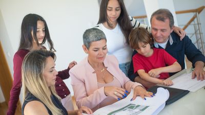 Familia de cinco personas revisa planos y papeles alrededor de una mesa, sobre partición de herencia Chile