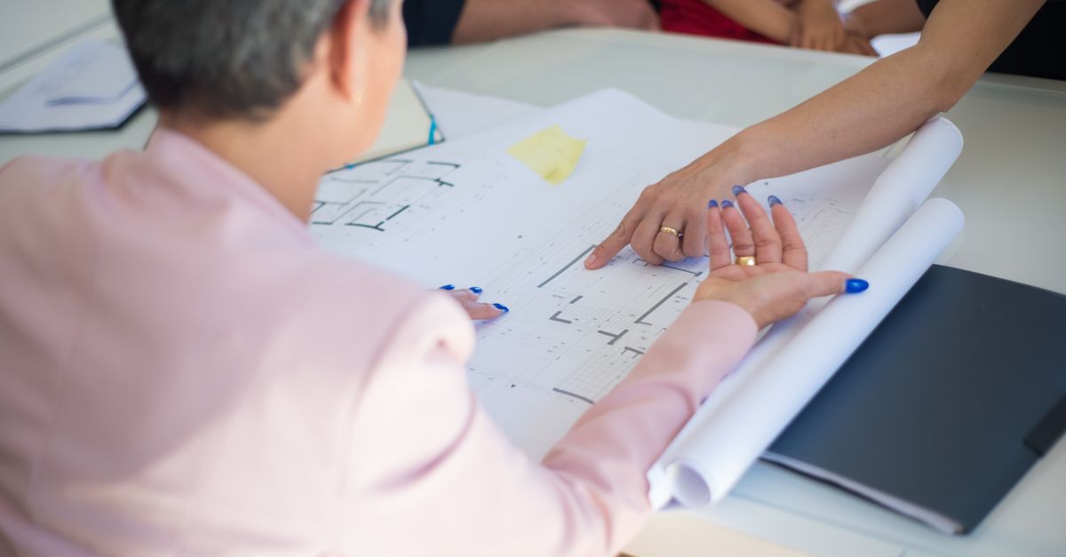 Group discussing architectural floor plans in an office setting.