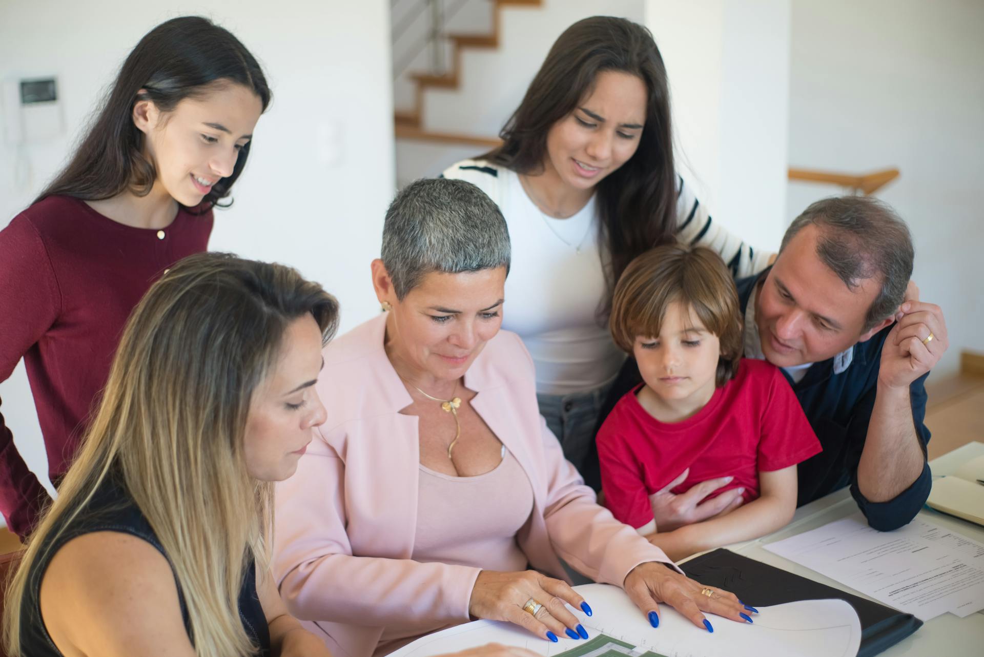 A family discusses real estate documents at home with a realtor, fostering communication and planning.