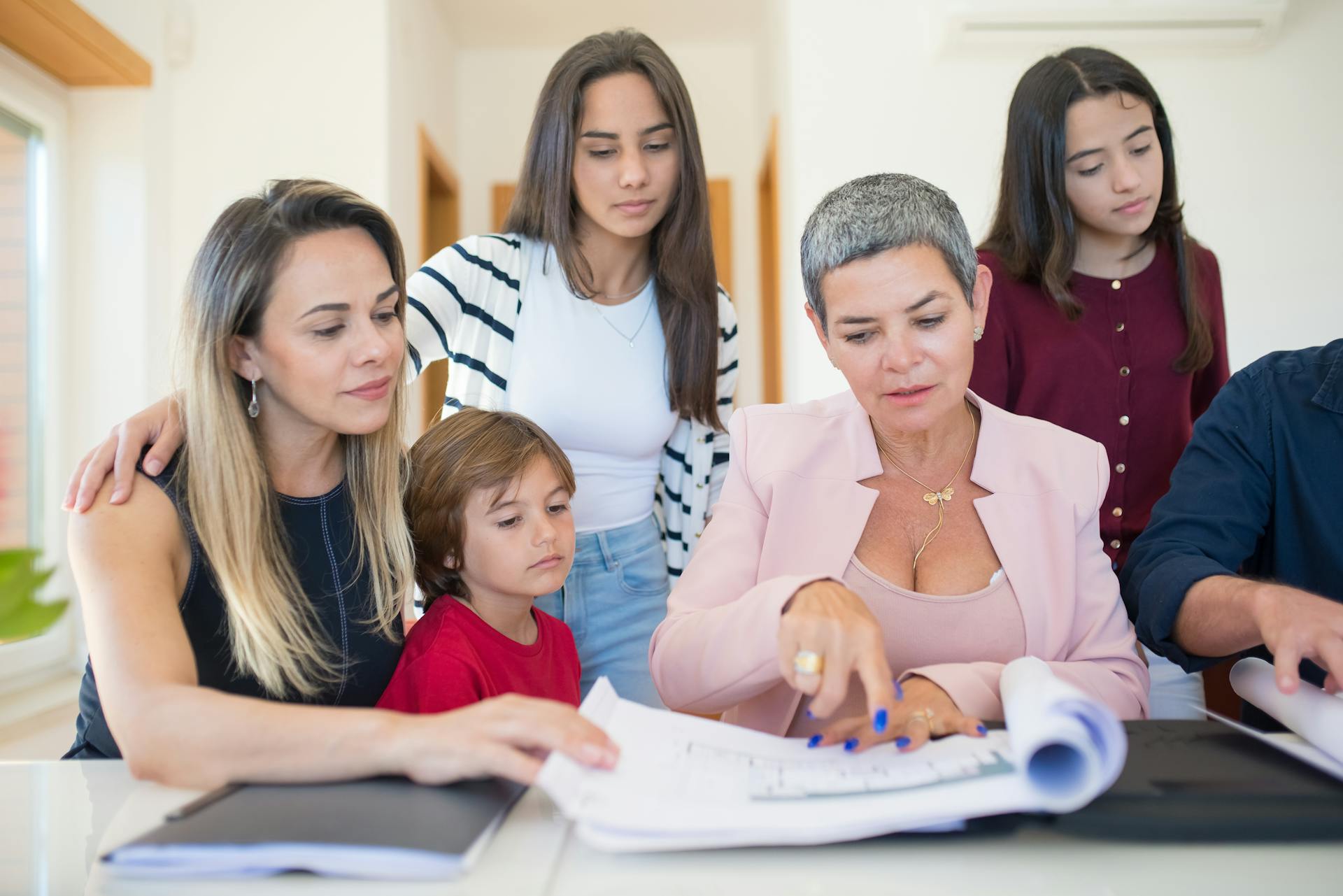 A family group reviewing real estate documents with a realtor indoors.