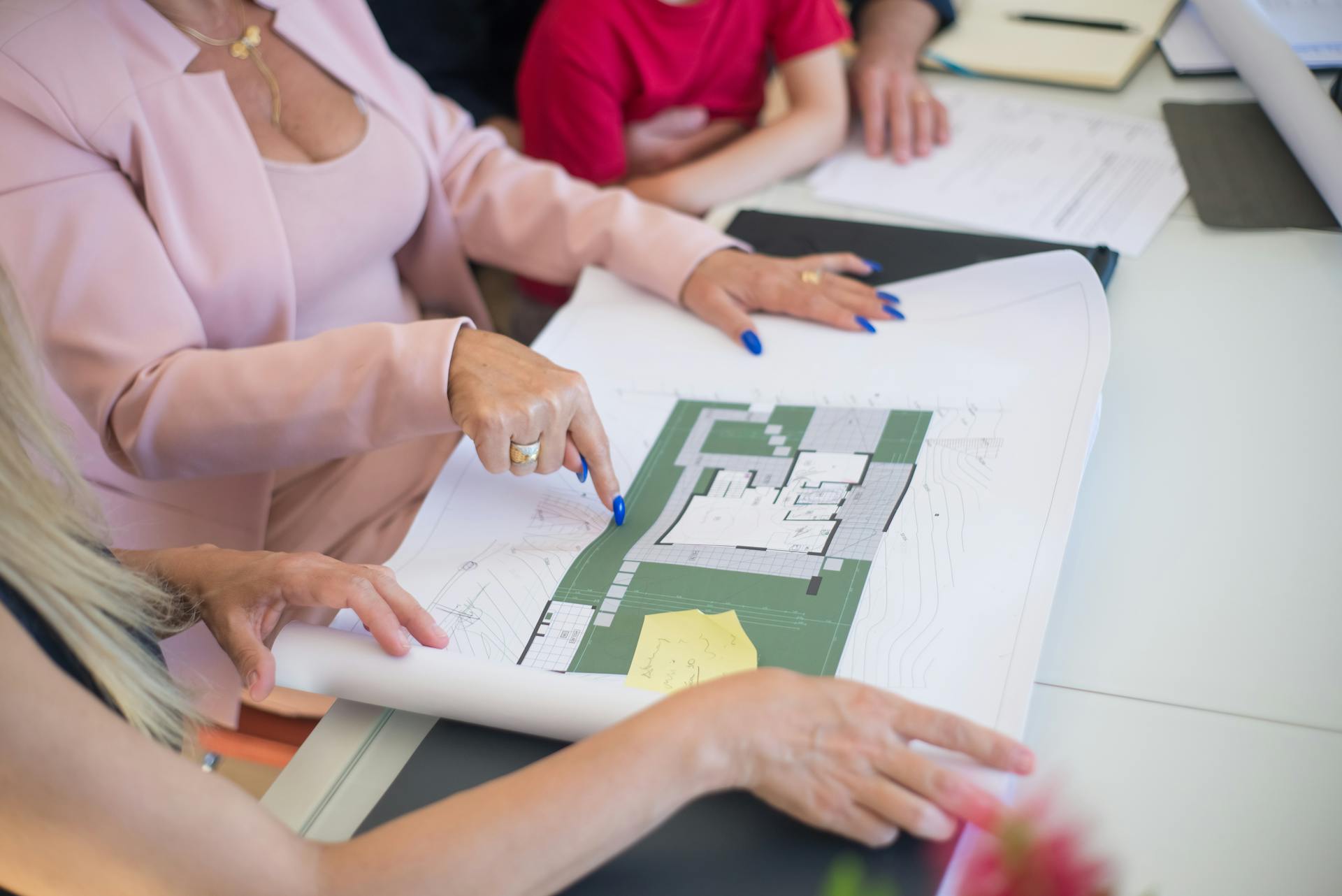 A Woman in Pink Blazer Pointing Finger on the Floor Plan