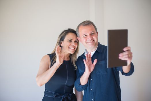 Smiling couple having a video call on a digital tablet indoors.