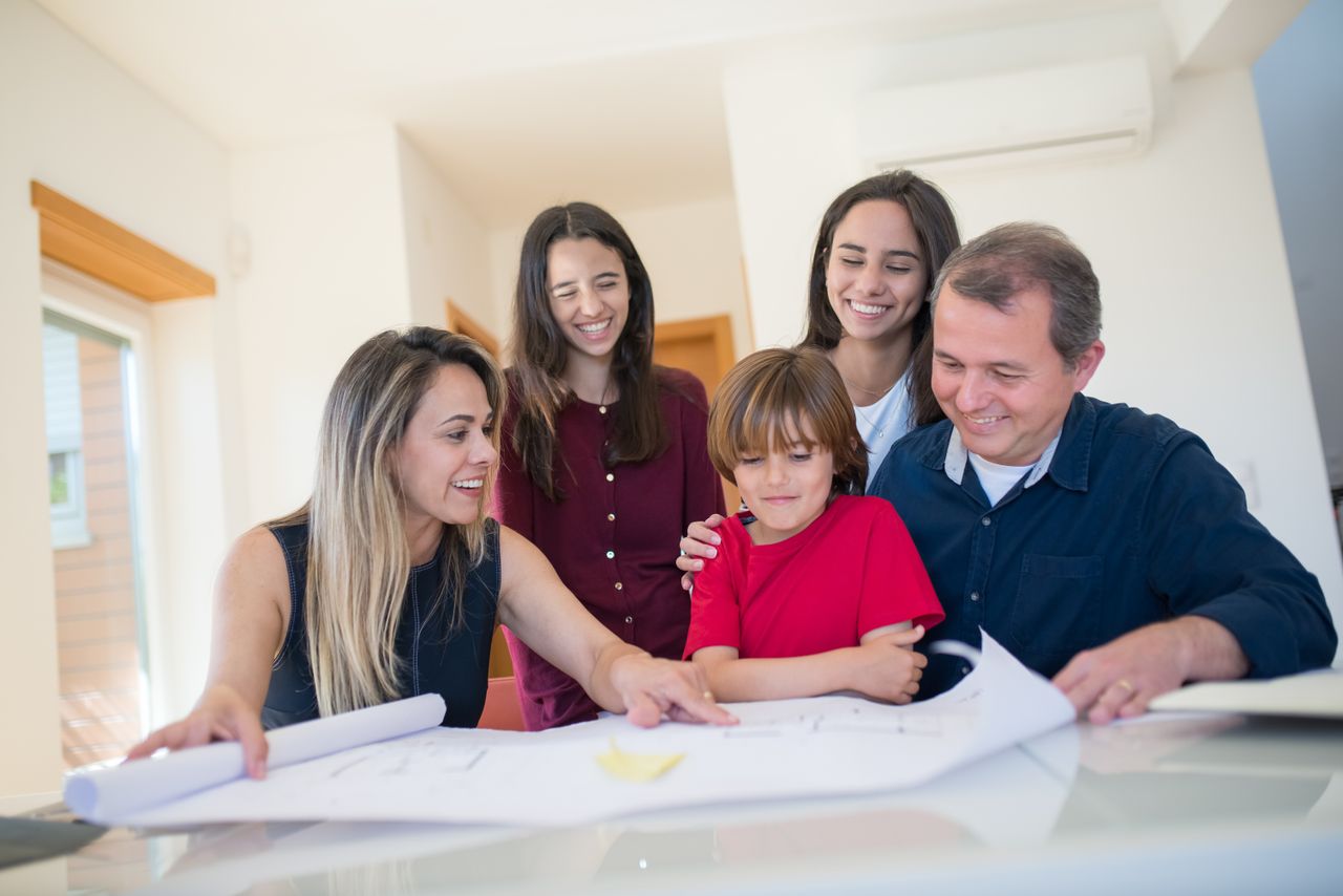 A joyful family gathered around a table reviewing a home blueprint together.