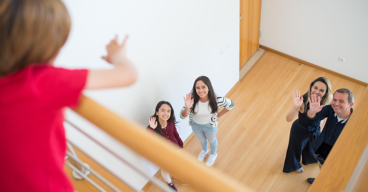 Family waving up at a person in a modern indoor setting, conveying warmth and connection.