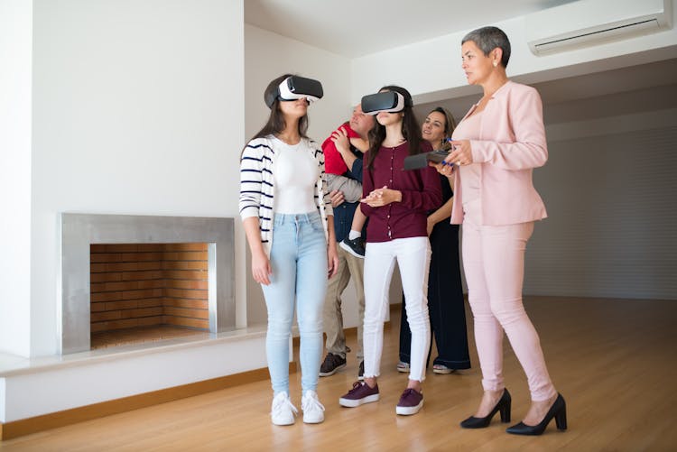 Real Estate Agent Showing A House To A Family Through Virtual Reality Goggles 