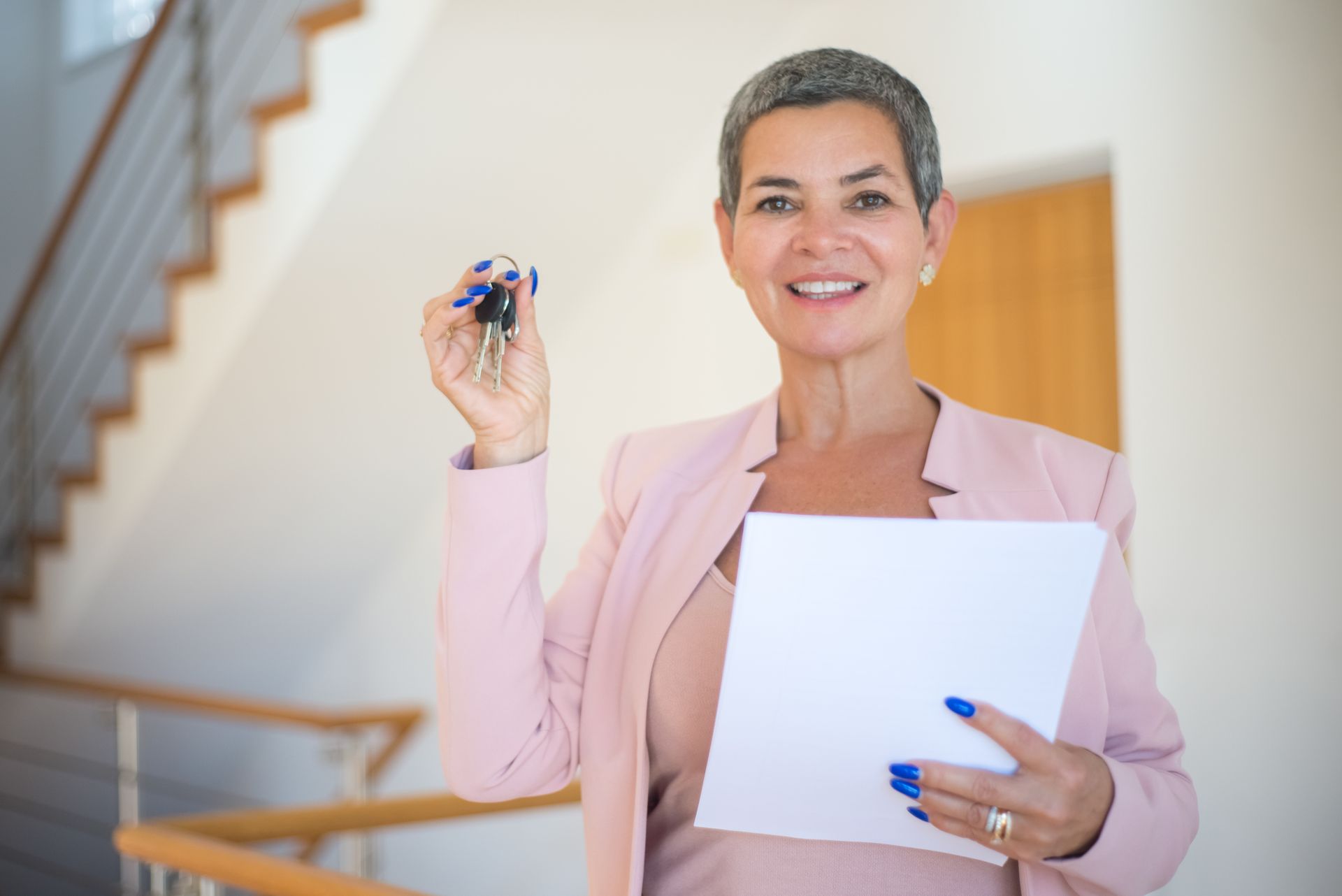 Woman in Pink Blazer Holding White Paper and Keys