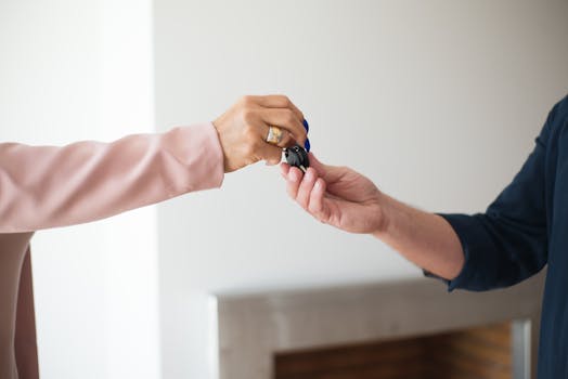 A close-up photo depicting the exchange of keys between two adults, symbolizing a real estate transaction.