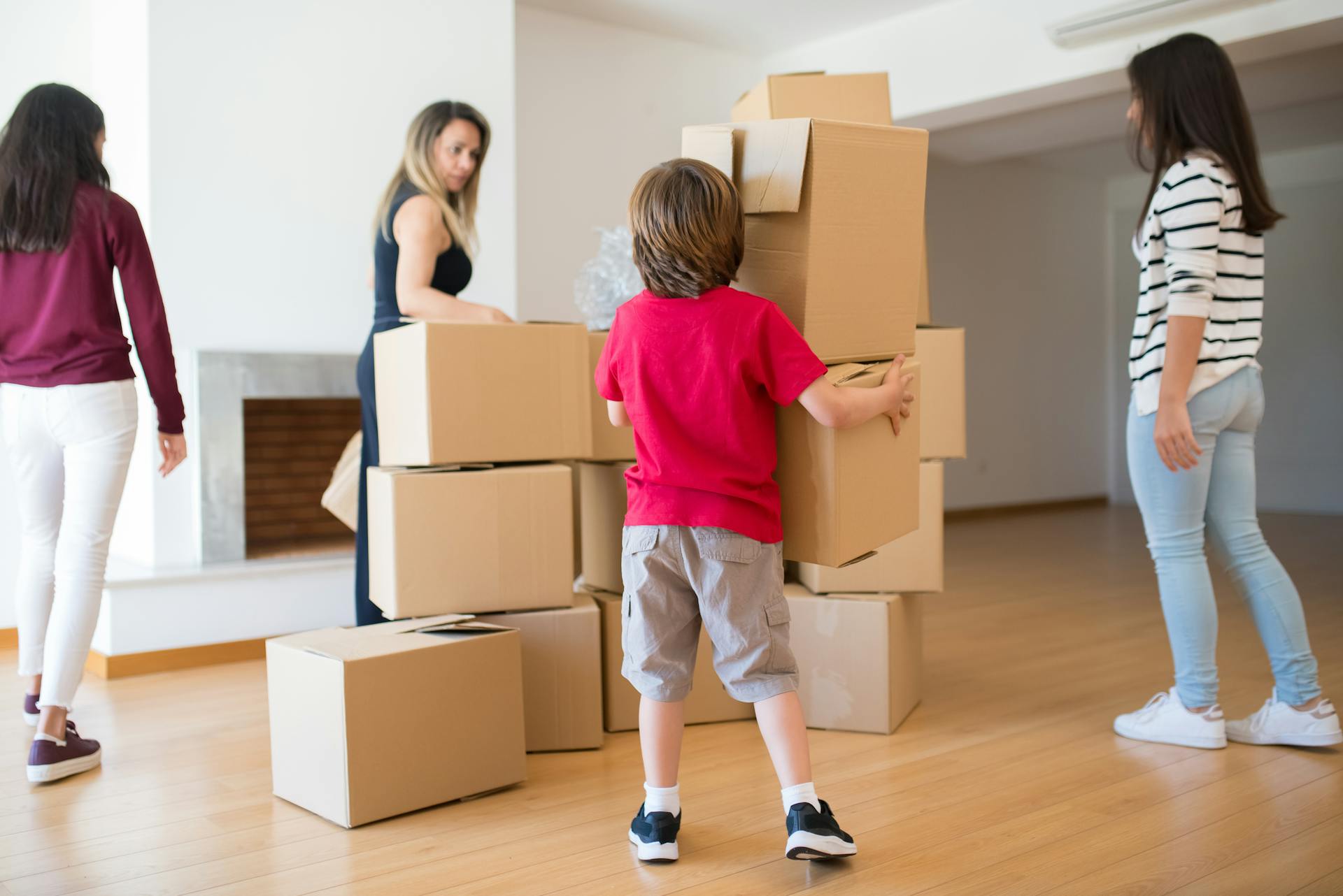 Family organizing and moving cardboard boxes in a bright room, creating a lively relocation scene.