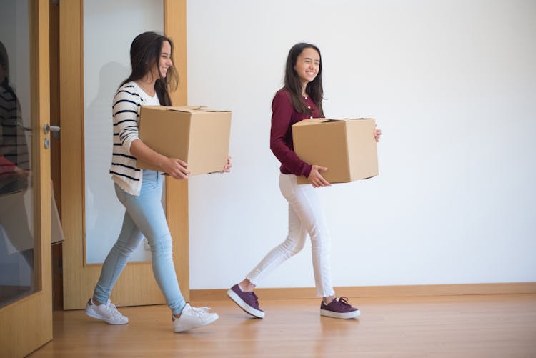 Two Women Carrying Cardboard Boxes