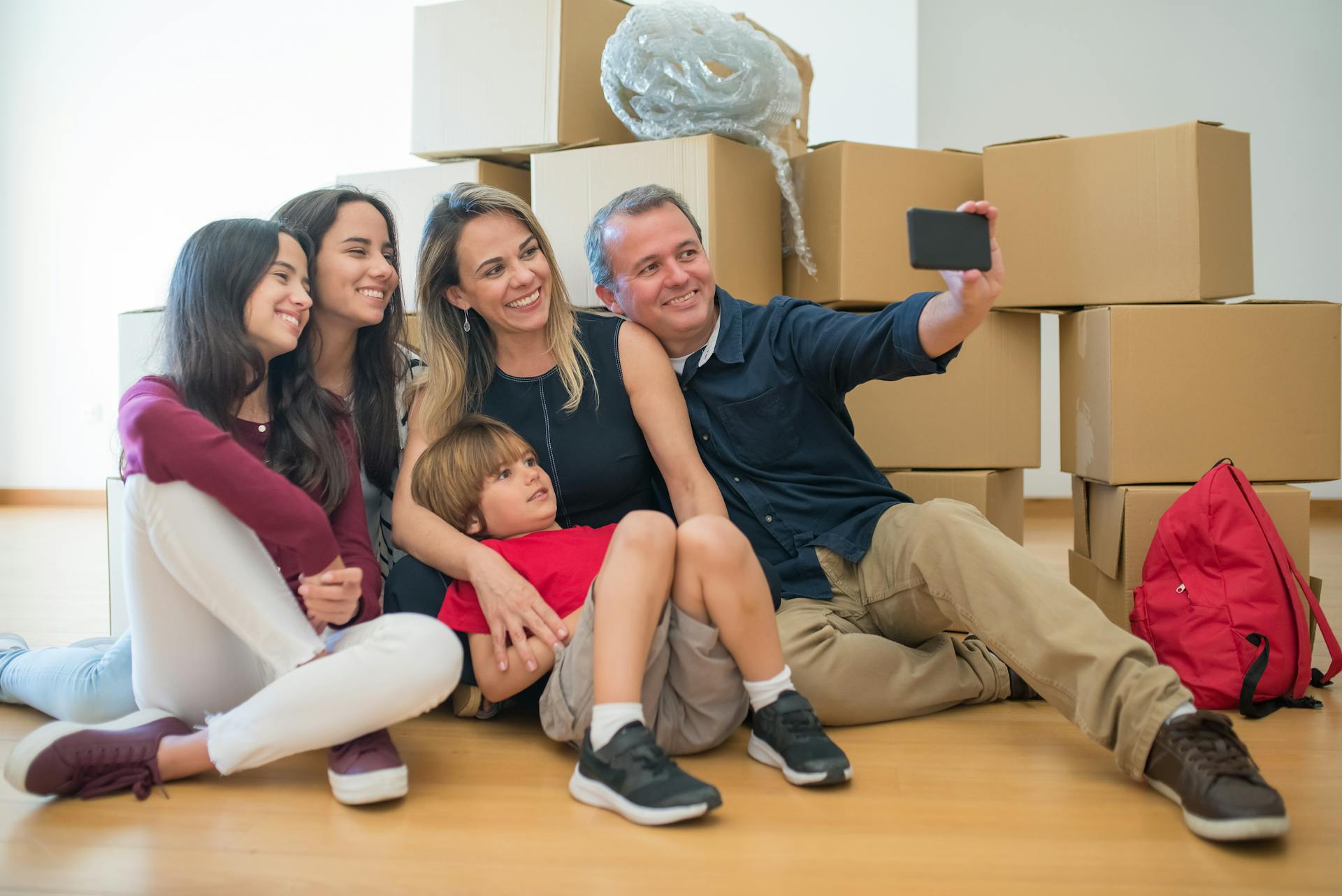 A joyful family capturing a selfie while surrounded by moving boxes in their new home.