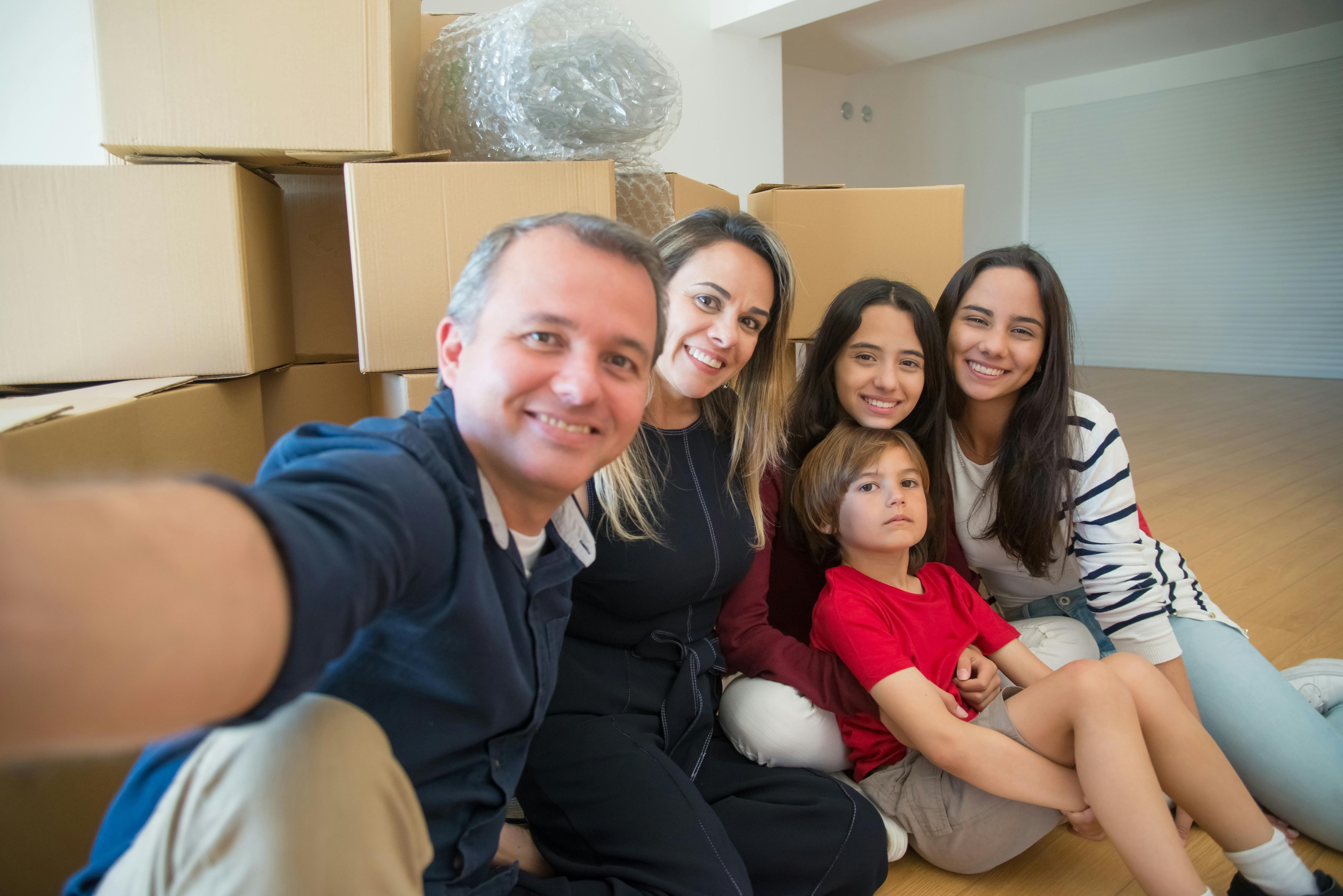 Almanya'da yeni bir hayata başlayan, ellerinde bavullarıyla gülümseyen mutlu bir aile ve çocukları.