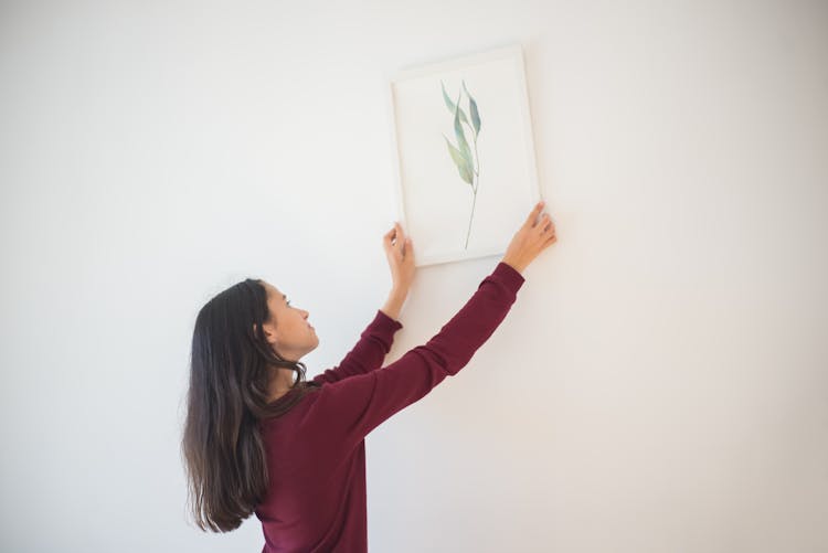 Girl Putting Frame On The Wall