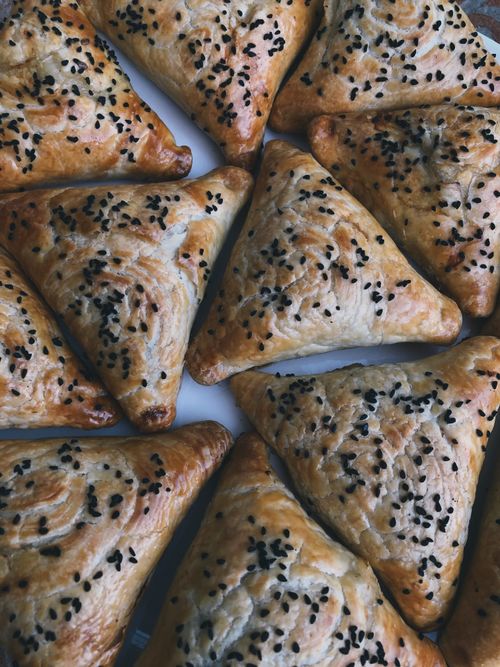 Free Golden triangular pastries sprinkled with black sesame seeds, perfect for a homemade treat. Stock Photo