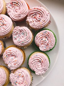 Top view of colorful cupcakes with pink frosting and sprinkles, perfect for dessert lovers.