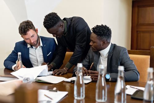 Free Three professionals working together at a table, discussing documents in an office setting. Stock Photo