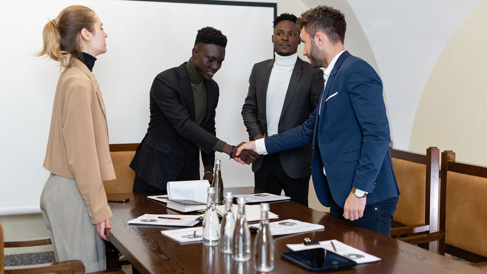 A diverse group of professionals engaged in a business meeting, sealing a deal with a handshake.