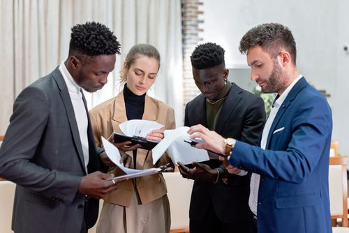 Free A diverse group of professionals in business attire reviewing documents in an indoor setting. Stock Photo