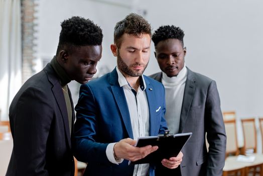 Three diverse business professionals collaborating indoors, focusing on teamwork.