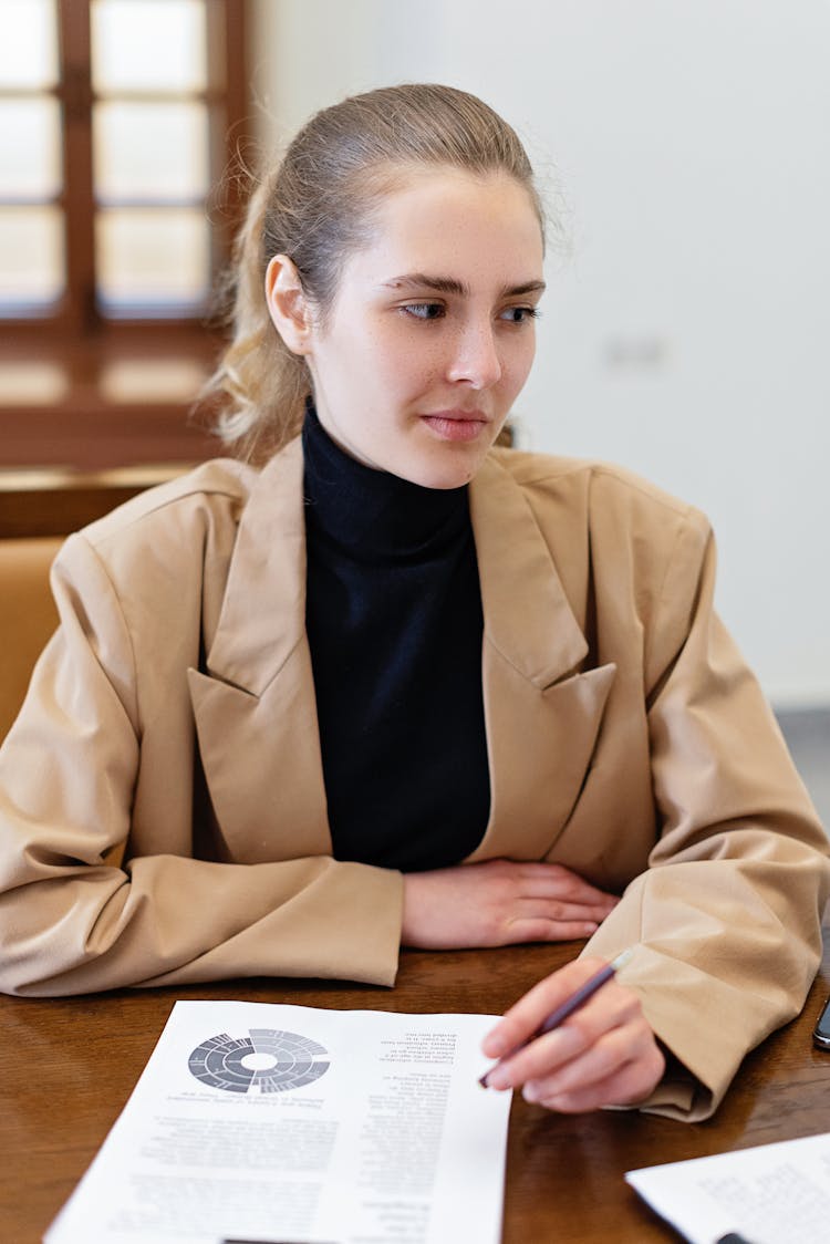 A Woman Sitting With A Pen And Papers