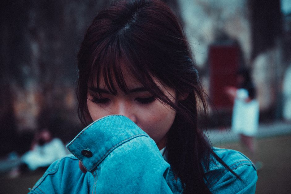 A young woman in a denim jacket reflects outdoors, creating a serene and thoughtful mood.