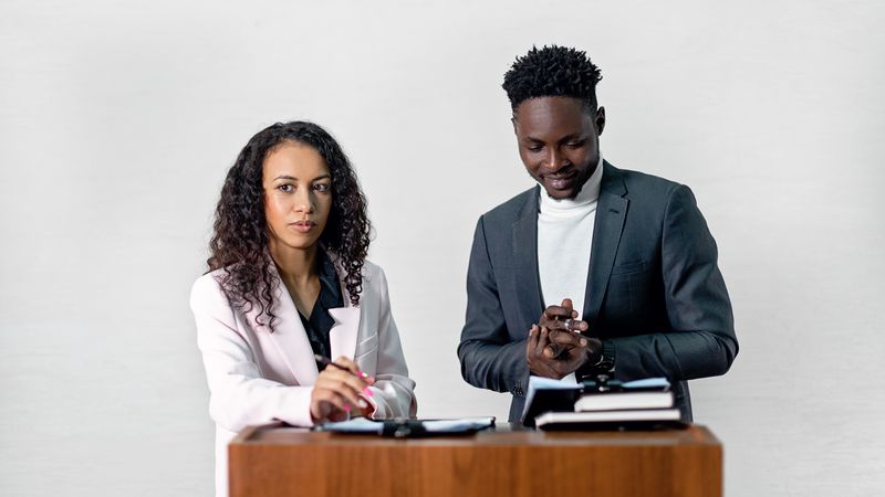 Two professionals at a podium speaking and engaging with an audience in a formal setting.