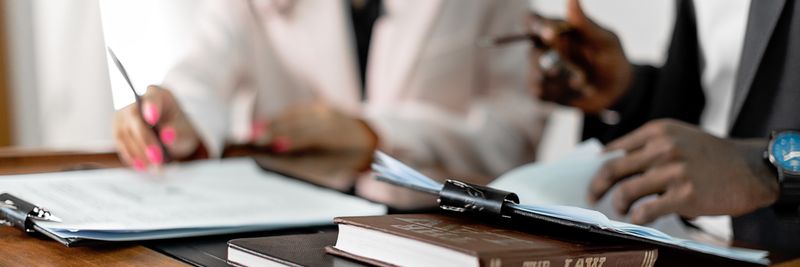 Two lawyers reviewing documents with law books on a desk. Professional legal environment.