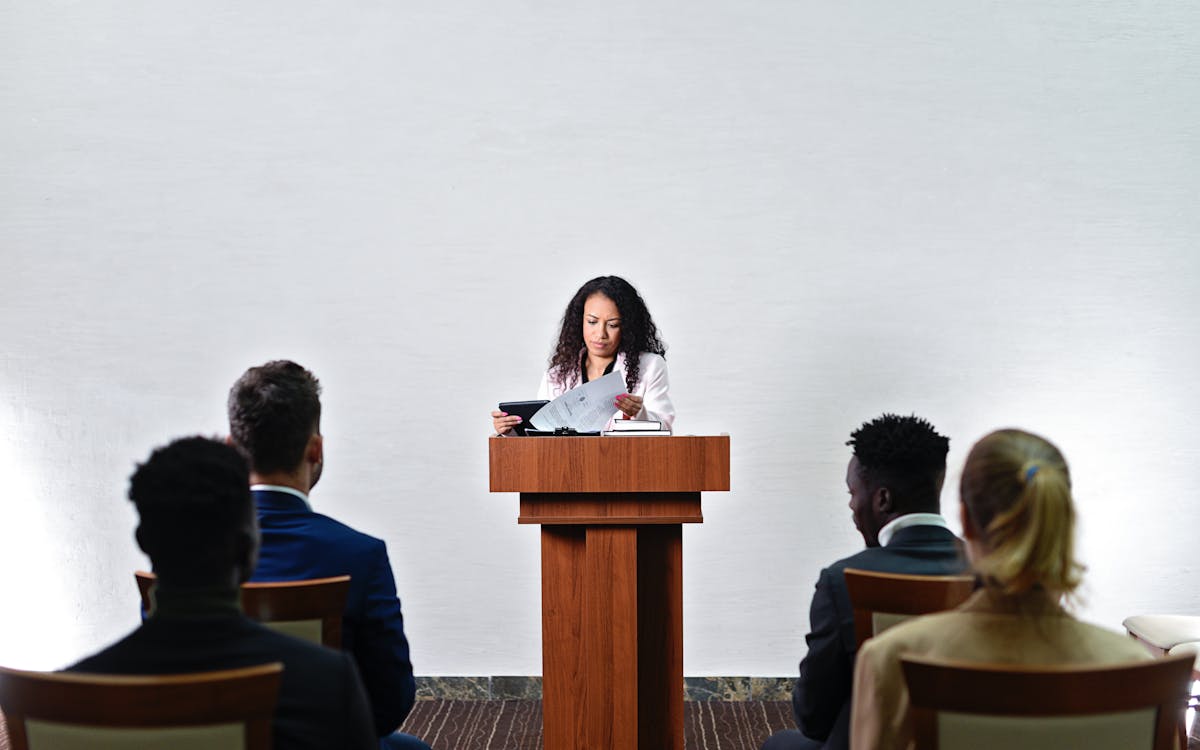 Confident woman delivering a speech to a diverse audience in a conference room.