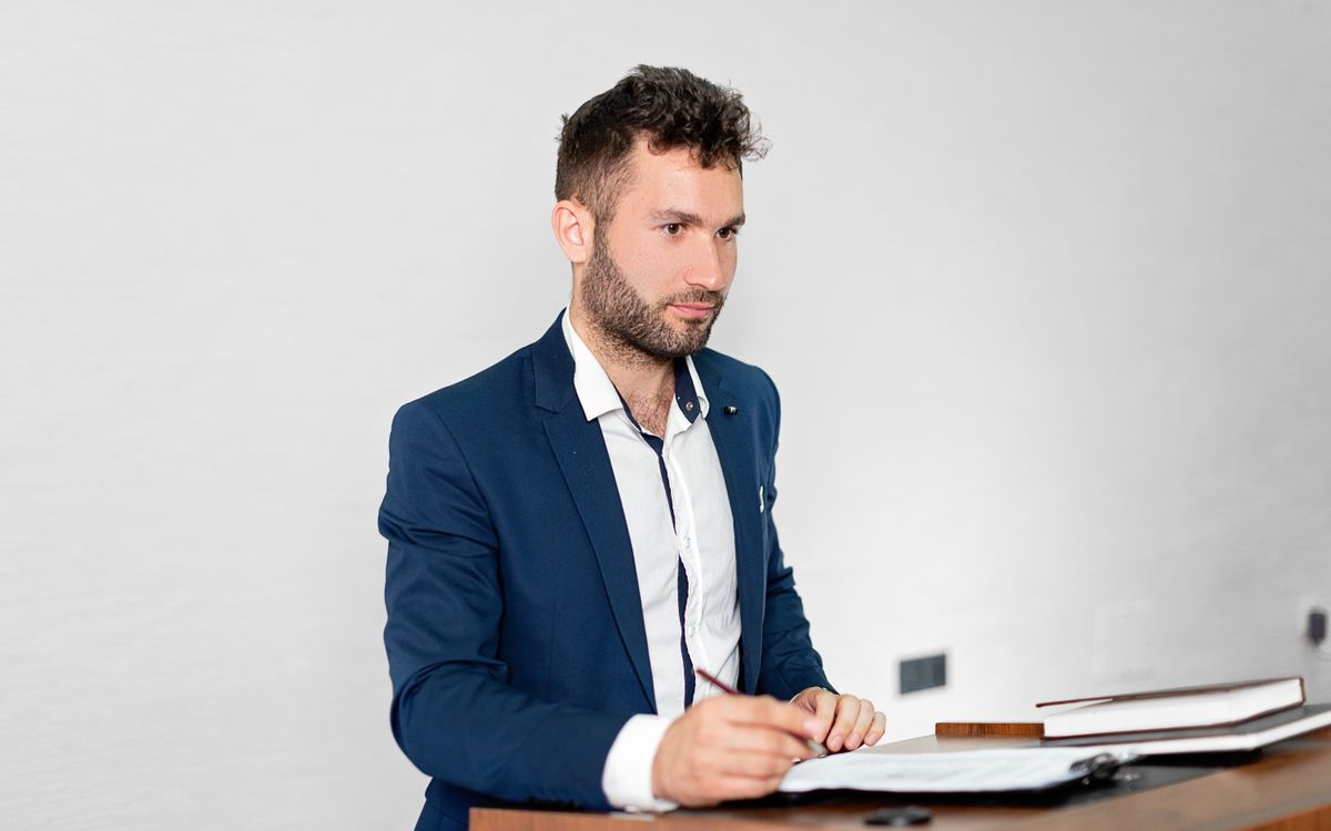 Confident businessman in a blazer presenting at a podium indoors.