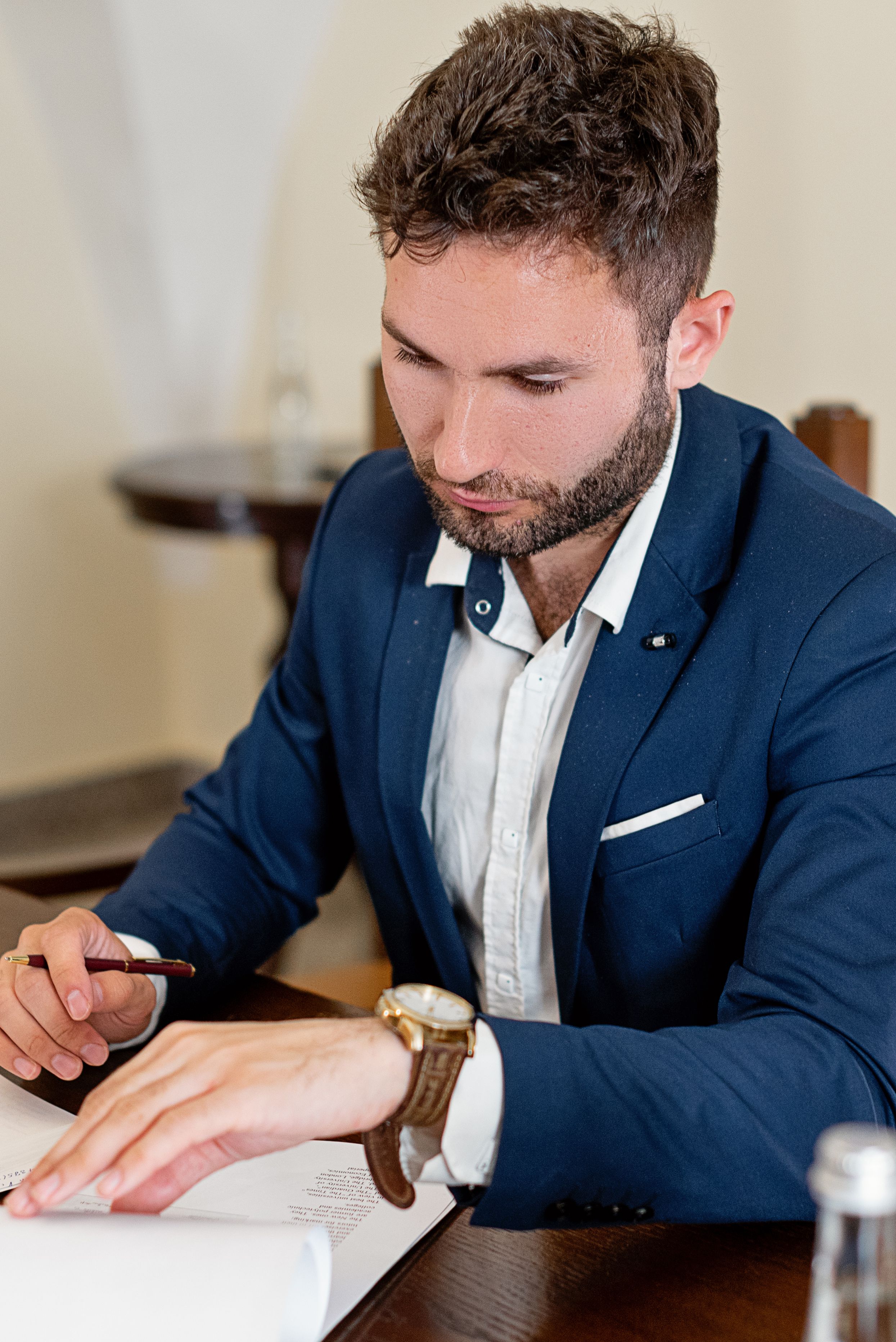 Businessman in a suit reading and signing important documents at a desk.