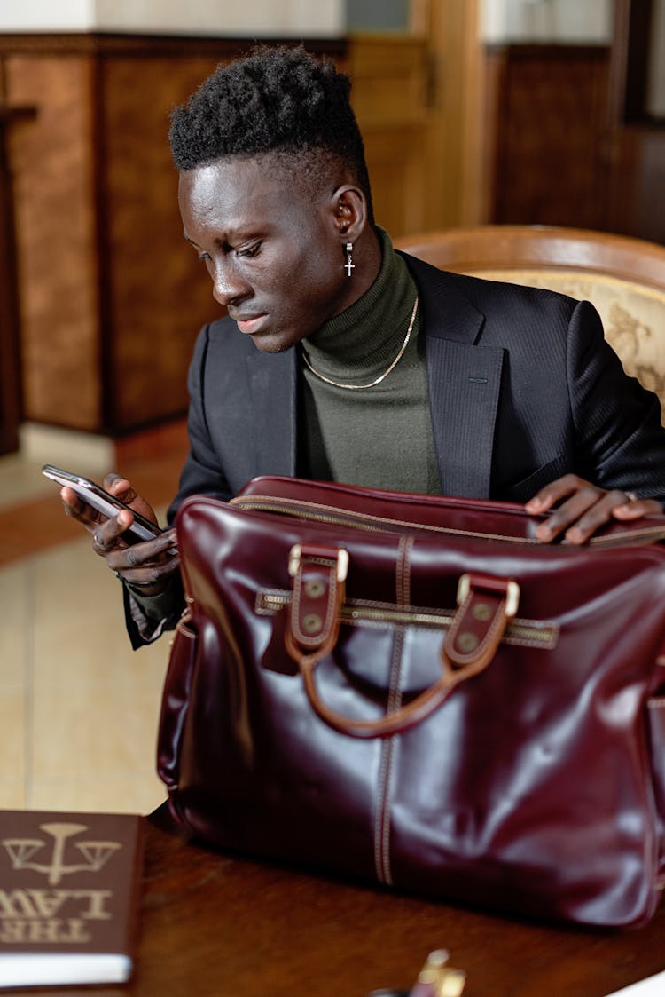 Man In Black Suit Jacket With Leather Briefcase Using Cellphone