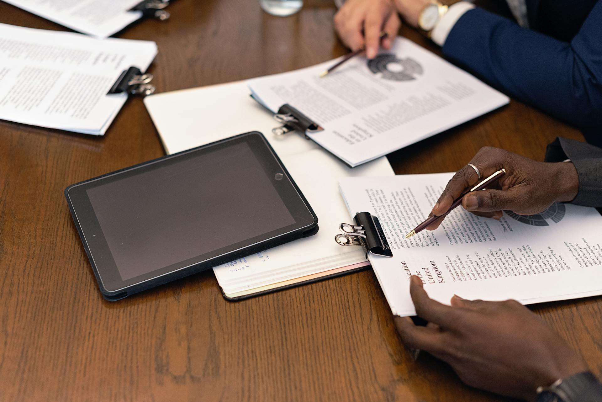 A business meeting with tablets and documents, showcasing digital integration in a professional setting.