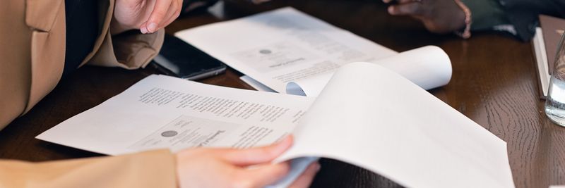Close-up of professionals reviewing documents during a business meeting in an office setting.