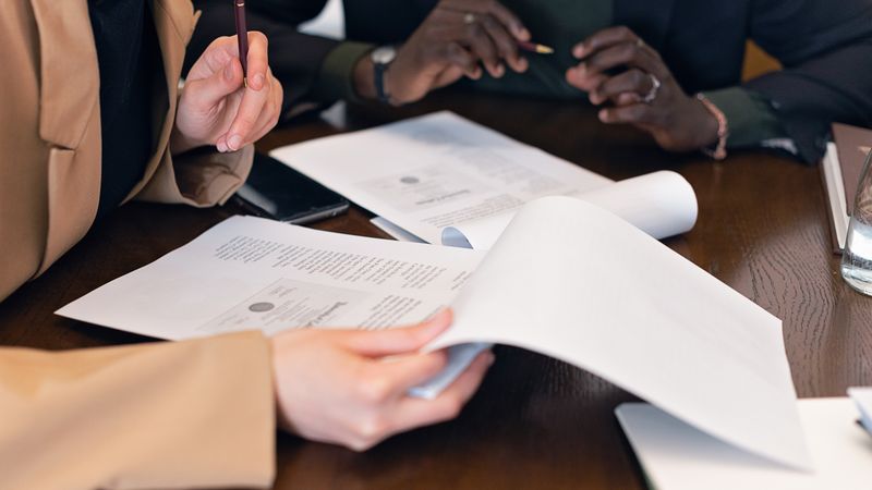 Close-up of professionals reviewing documents during a business meeting in an office setting.