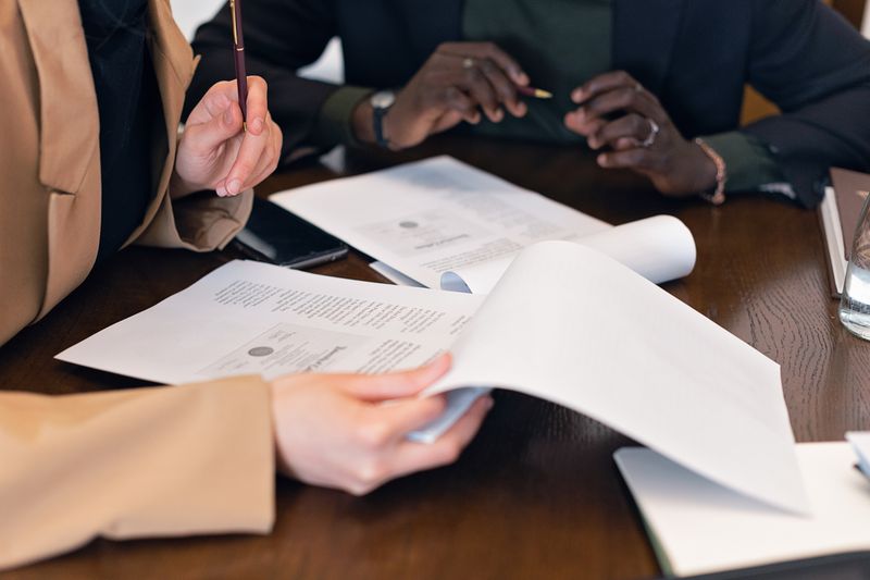 Close-up of professionals reviewing documents during a business meeting in an office setting.